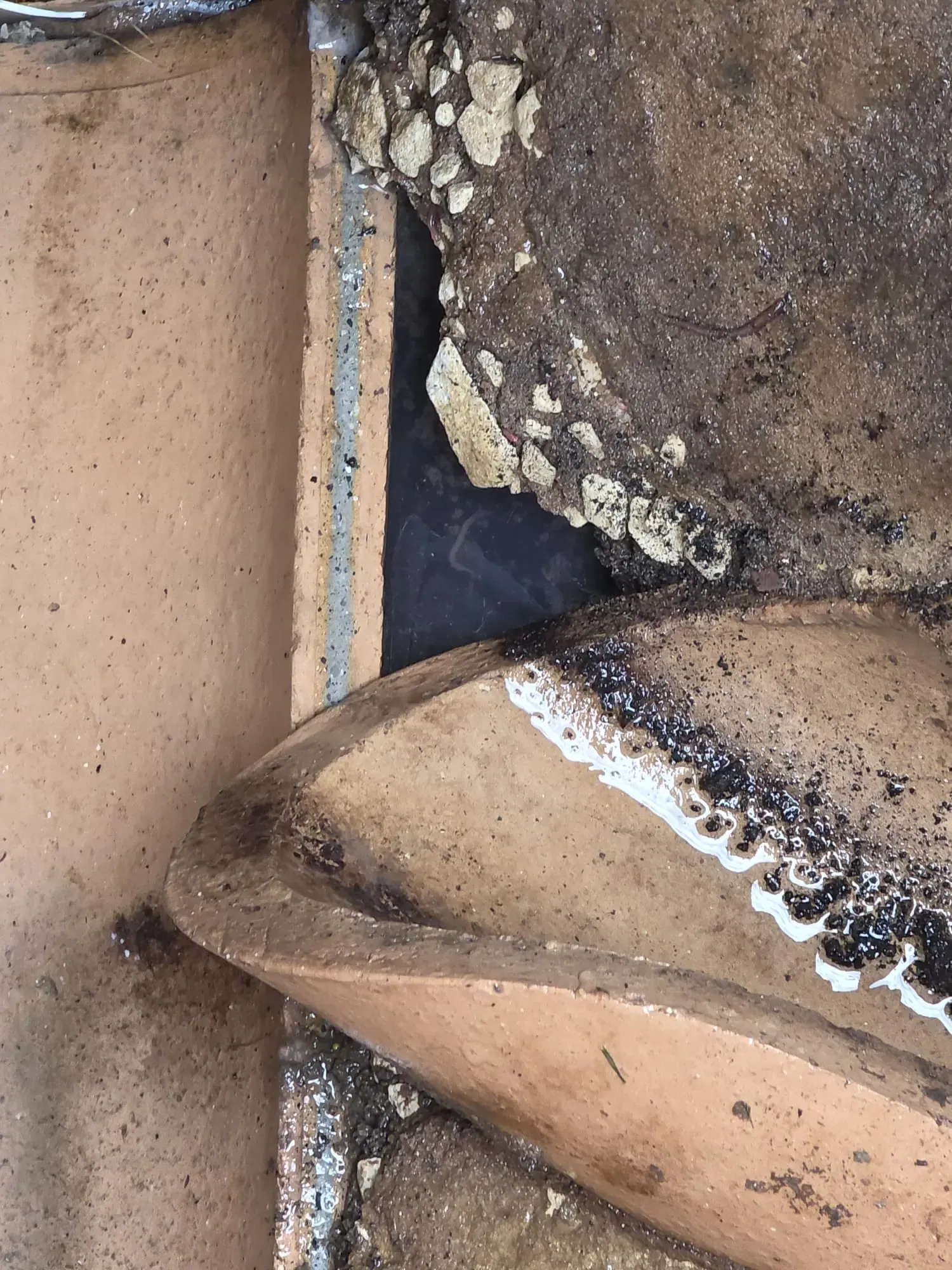 Broken clay drainage pipe with exposed concrete.